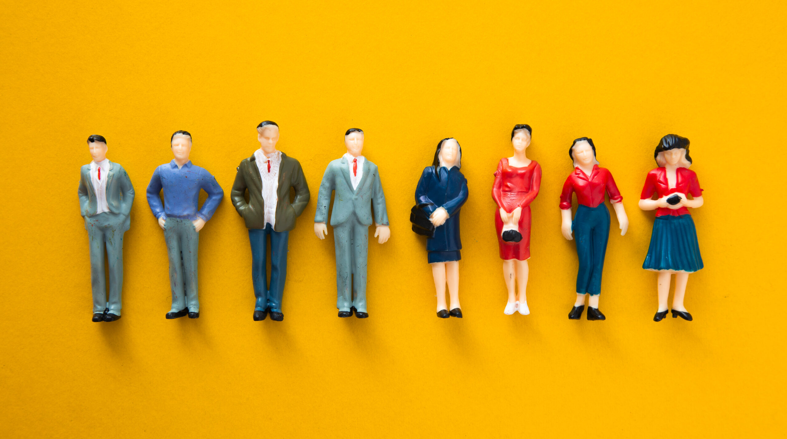 Persone in miniatura: uomini,donne,professionisti su sfondo giallo che icarnano il concetto di Buyer persona o cliente tipo