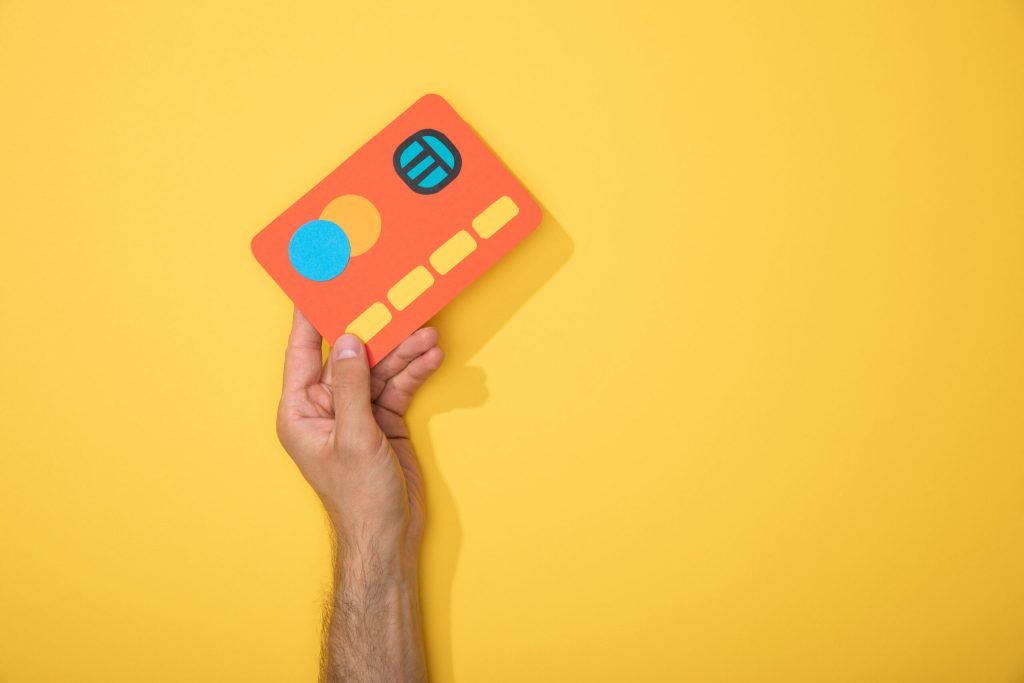 immagine con sfondo giallo in cui si vede una mano di un uomo che mostra una card per la raccolta delle recensioni ai fini di una buona strategia di local marketing